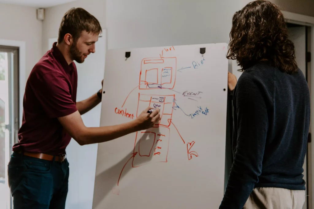 man writing something on a white board