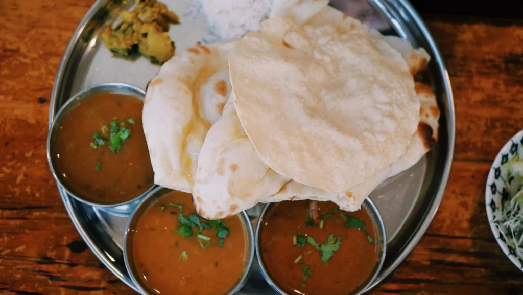 bread with brown soup next to it served on a silver plate