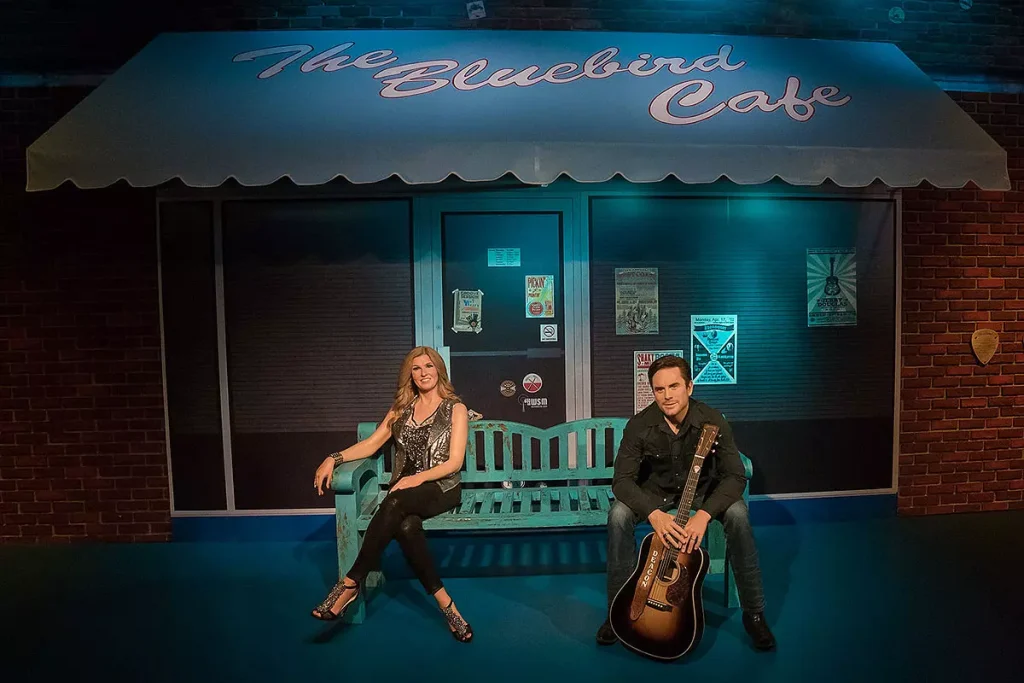 a guy with a guitar and a girl sitting infront of a shop