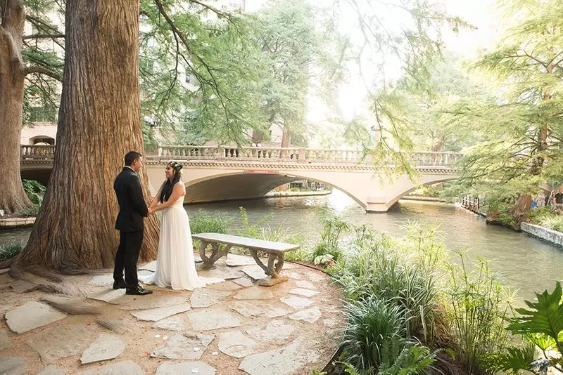 a couple infront of a bridge above a little river