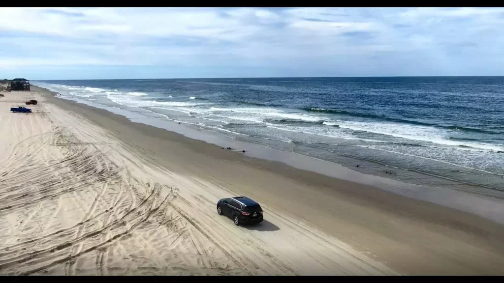 black car riding on the beach