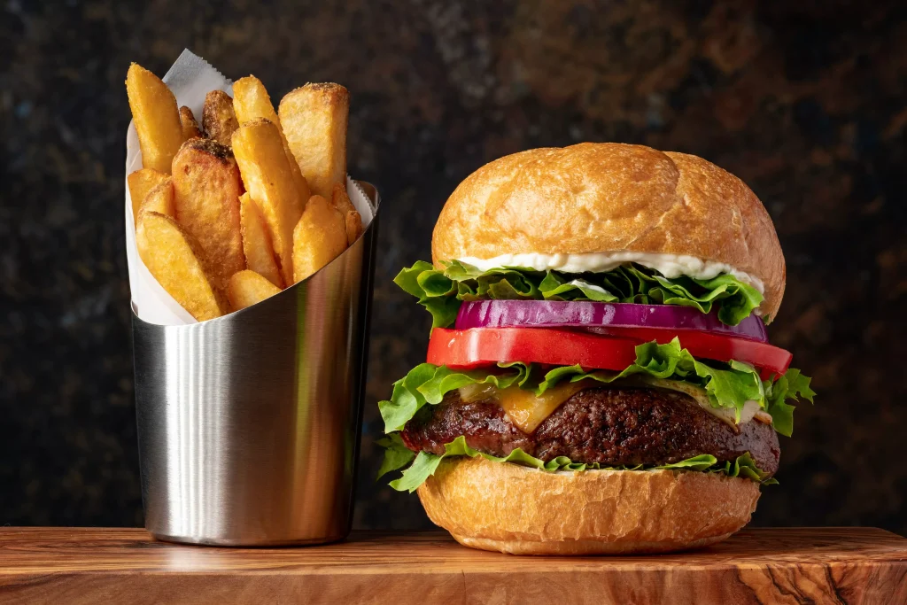 a burger with tomatoes and salad and fries next to it