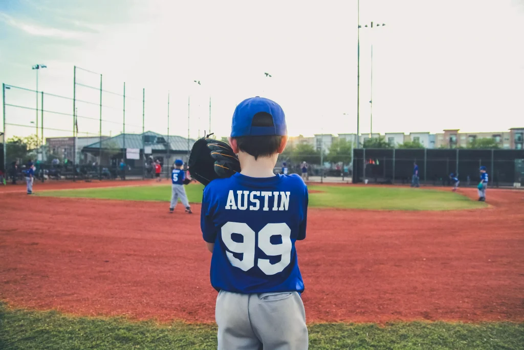 boy in a blue and white shirt standing on a baseball field