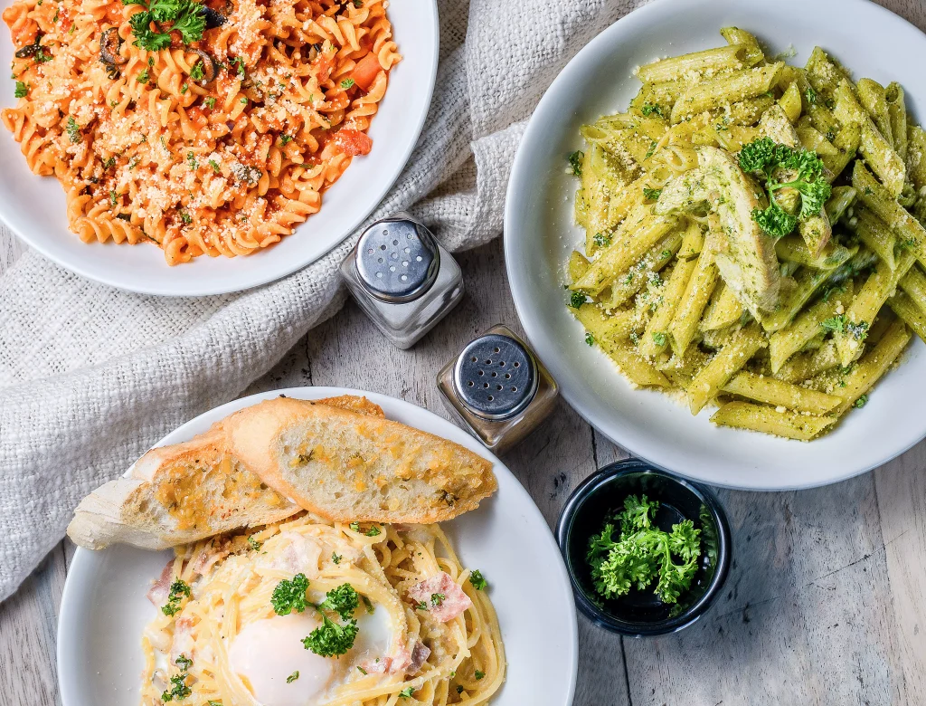 pizza pasta and bread next to salt and pepper