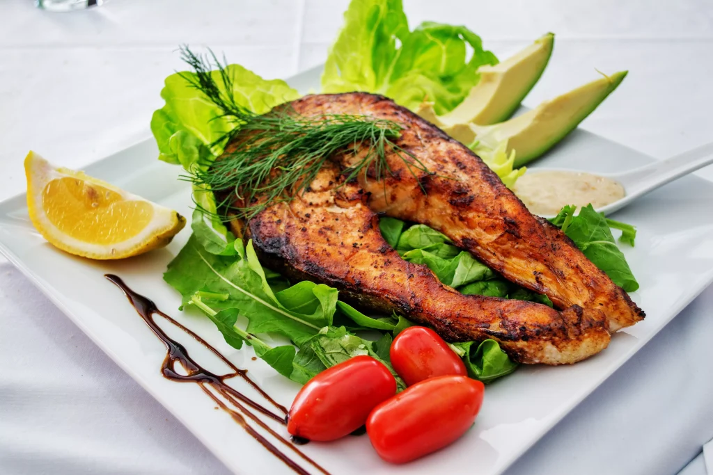 grilled seafood next to lemon and green salad