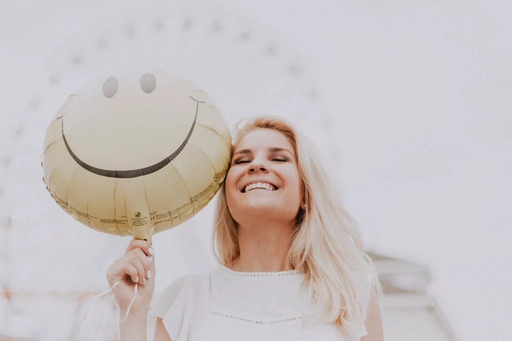 a blonde girl in a white top holding a baloon