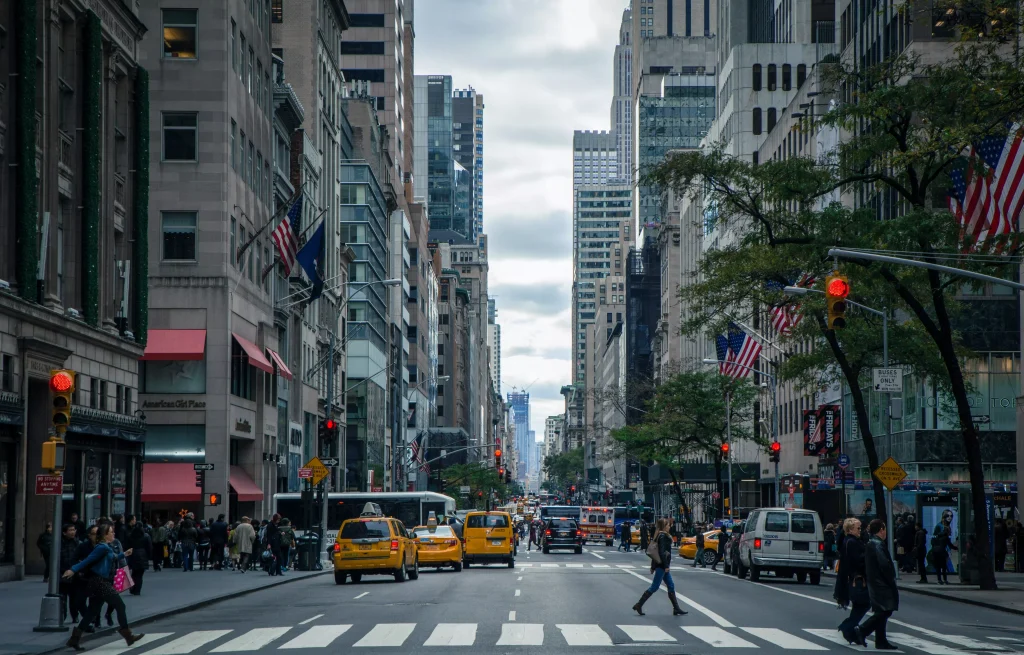 a street in a big city with traffic lights and people crossing the road