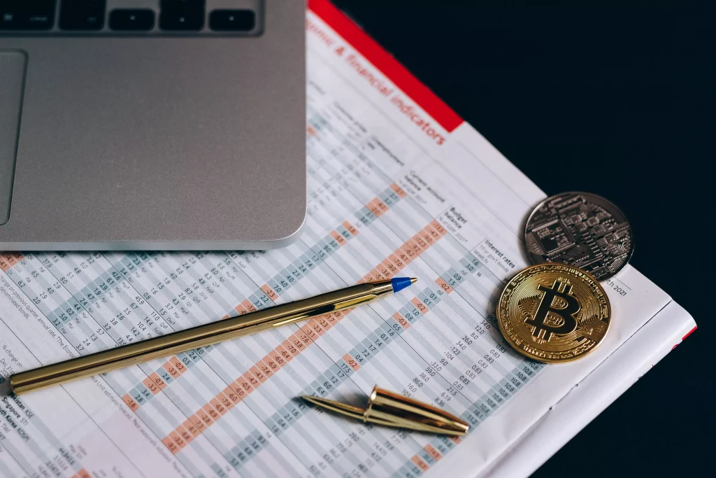 coins and a pencil on a notebook next to a laptop