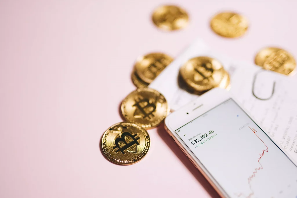 golden coins on a pink table next to a white smartphone