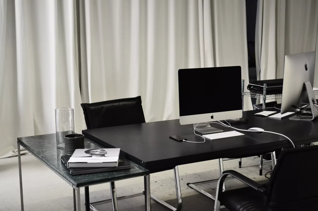 a office desk with a monitor keyoboard and a phone on it next to a chair