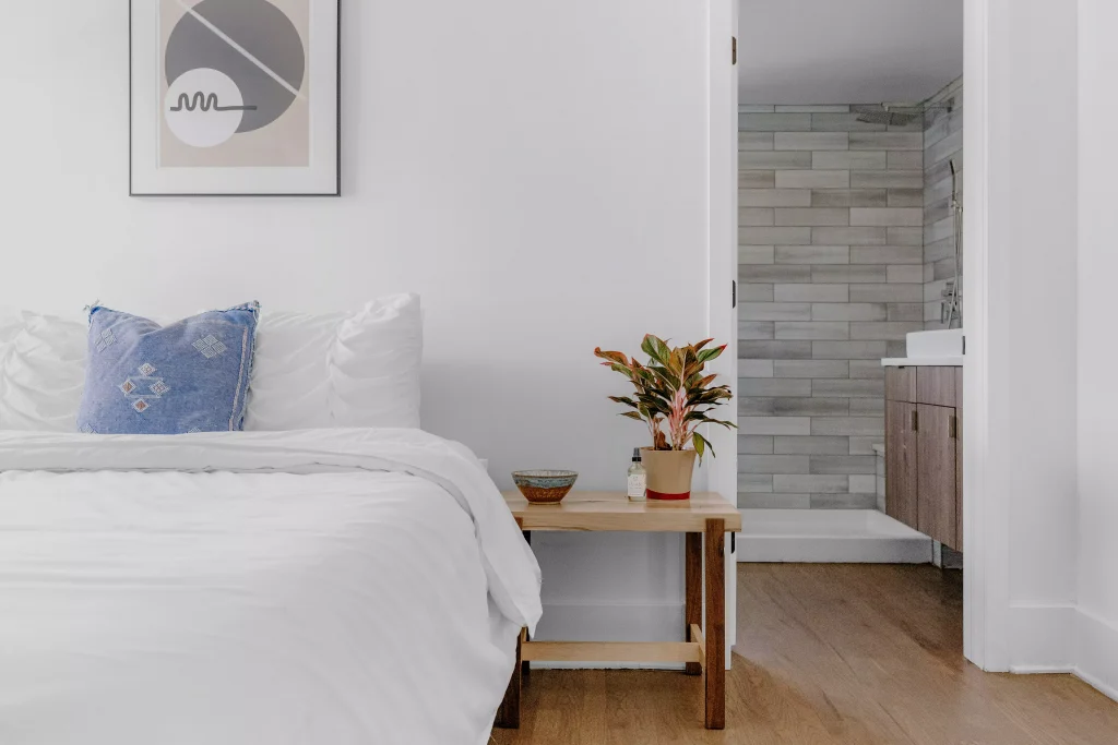 a bed with white pillows and brown table next to it