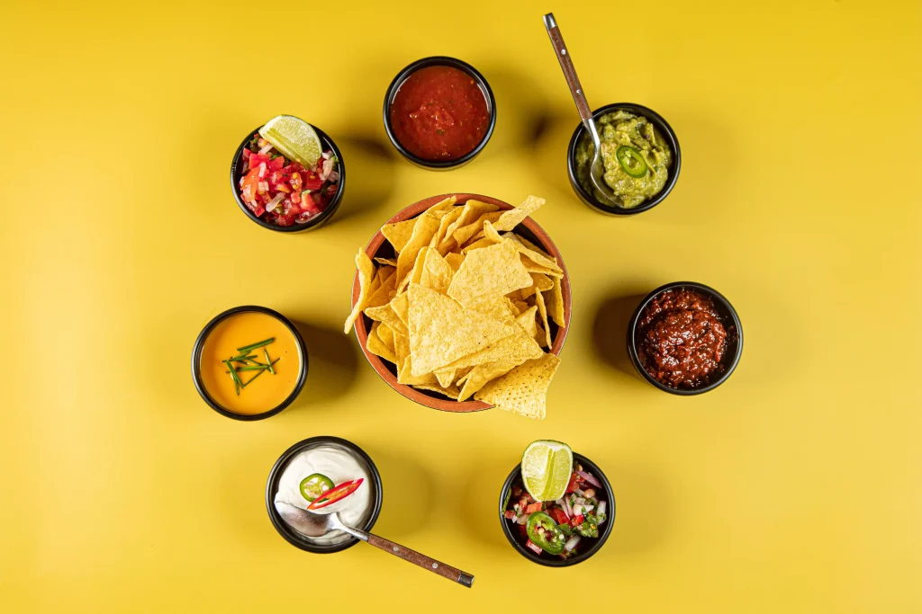 bowl of nachos and with dips around it