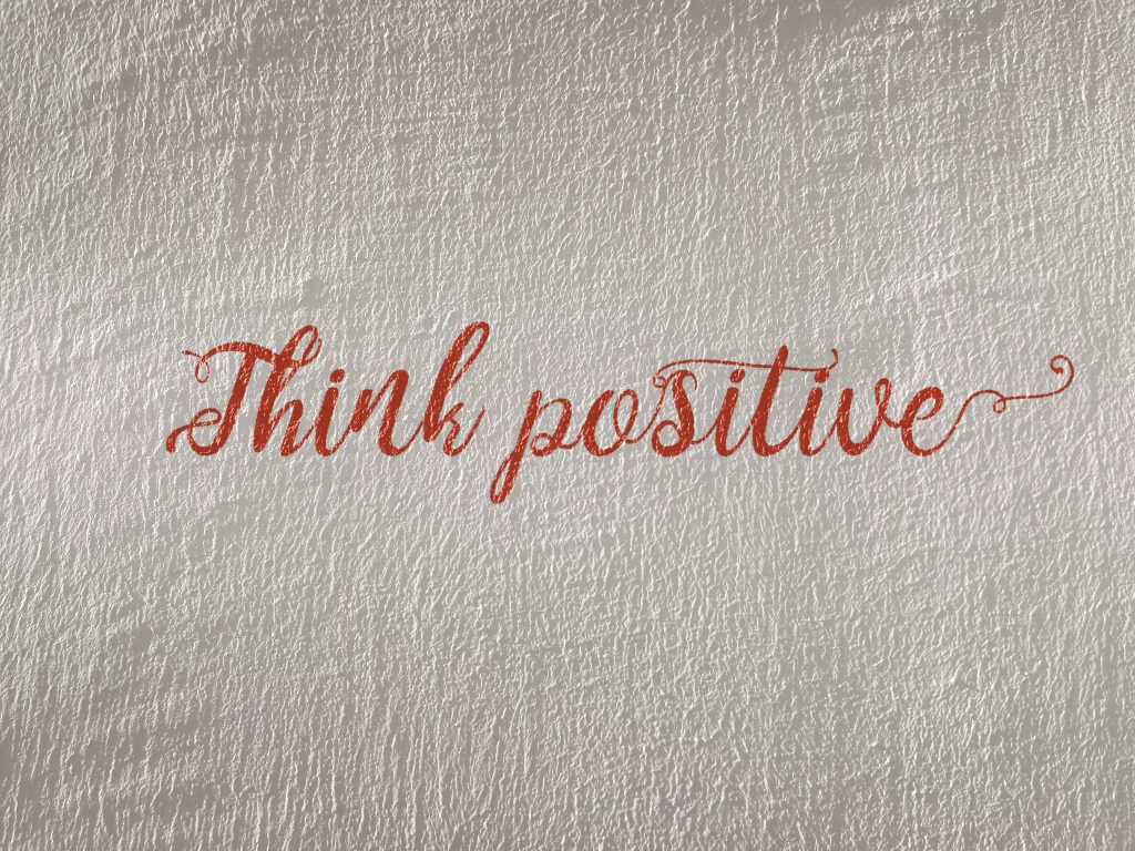 think positive written on a white wall with red letters