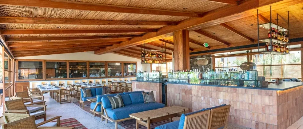 a restaurant with white tables and chairs and a brown wooden roof