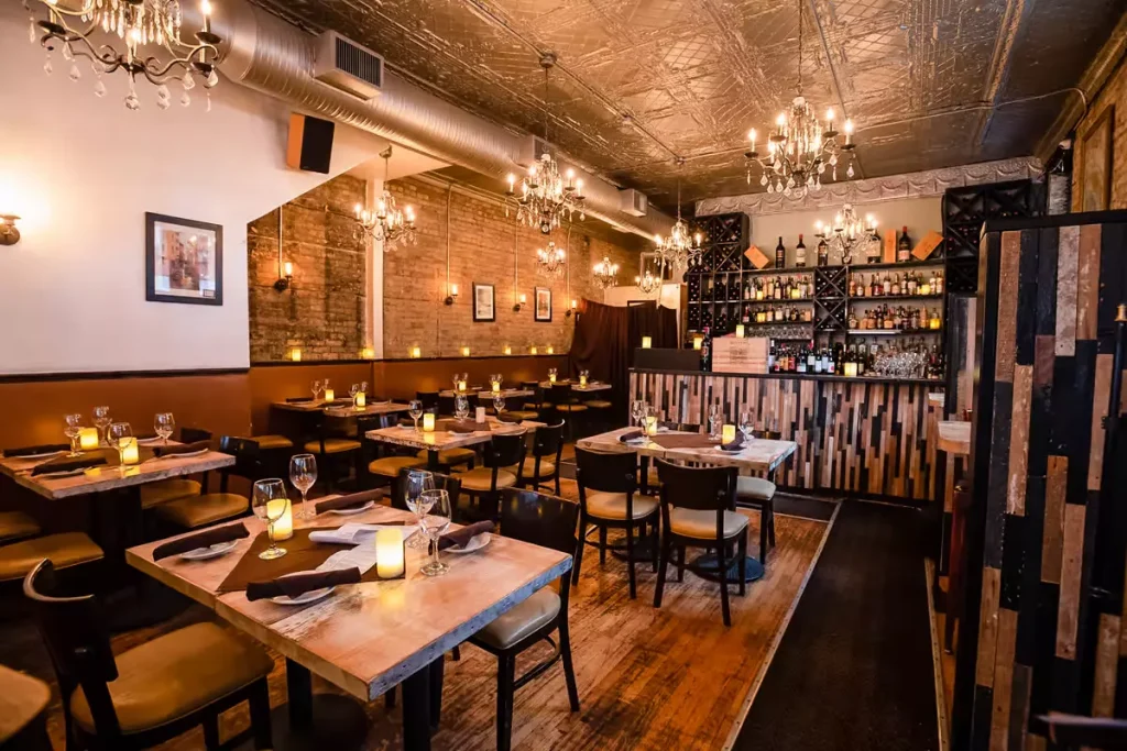 inside of a restaurant, with candles on tables and yellow lights all around