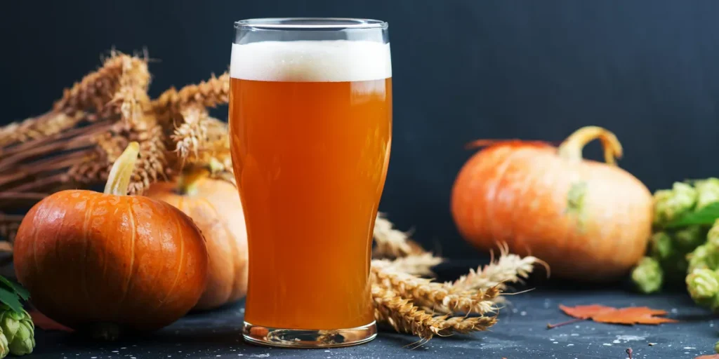 a glass of beer infront of pumpkins