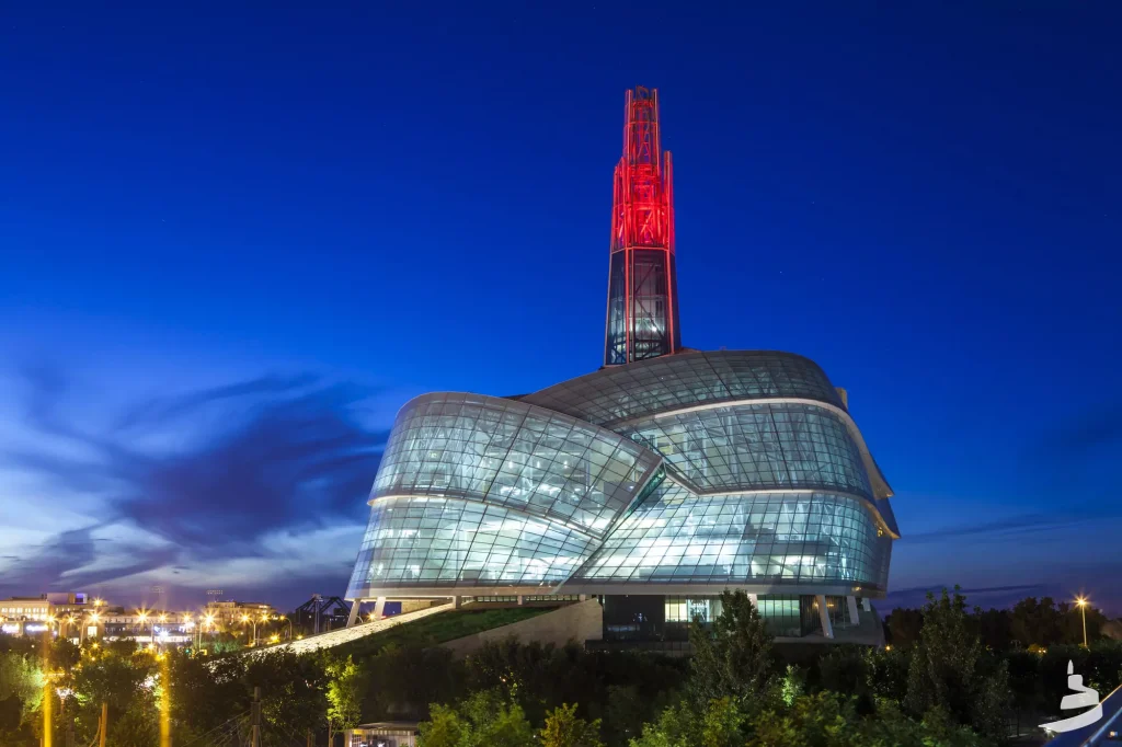 a big glass building with a red tower behid it