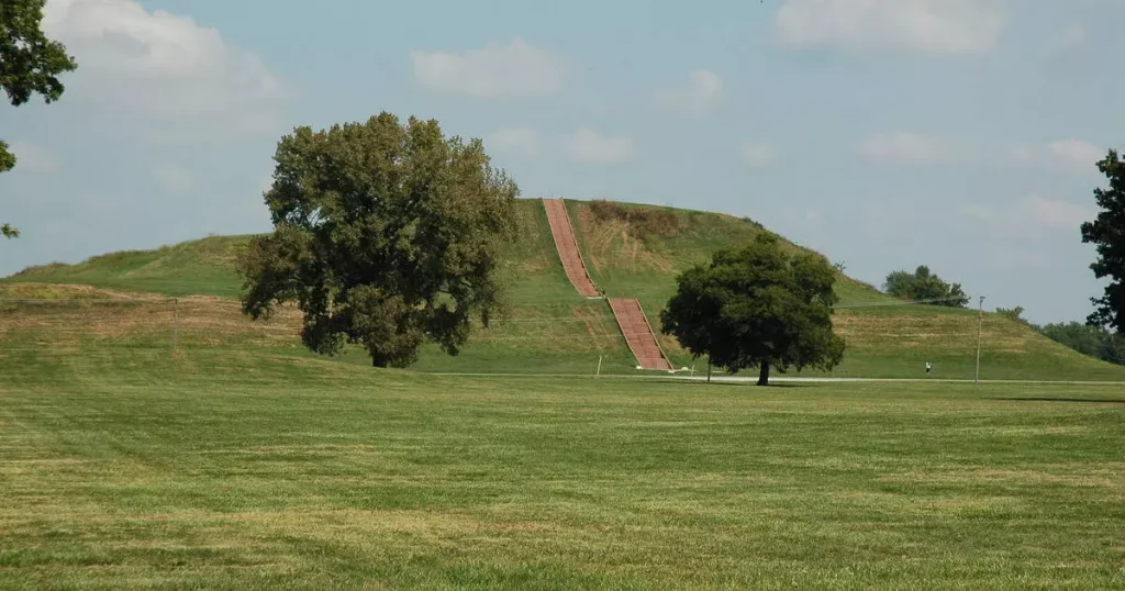 green field hills with two trees and stairs on them