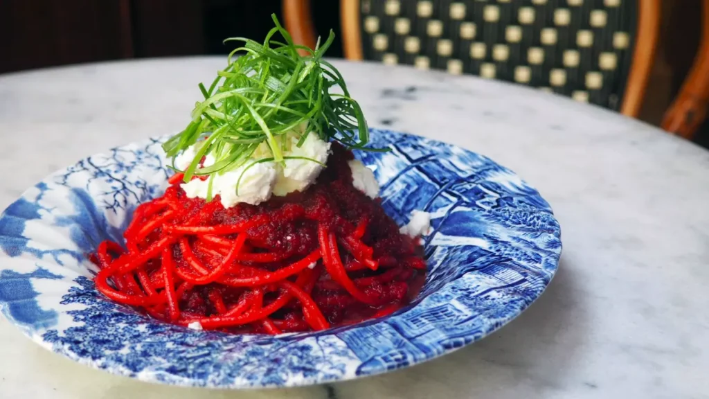 spaghetti with red sauce and green letuce in a blue porculan bowl