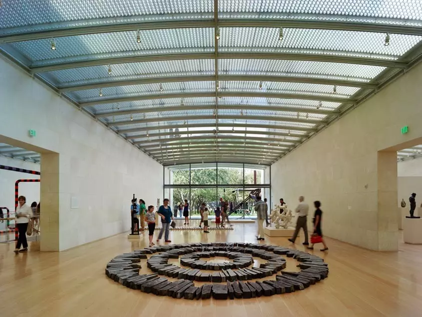 people in a building with a glass roof and a circle construction in the middle