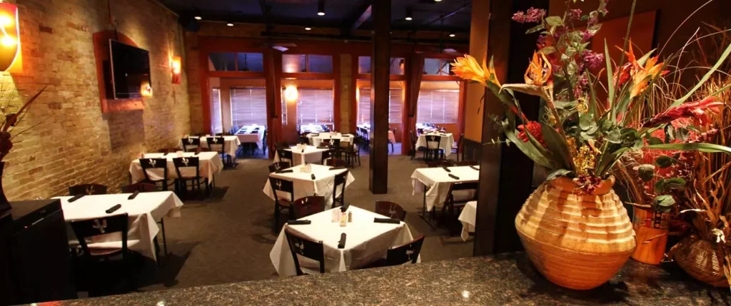 photo inside of a restaurant with white cloths on black color tables