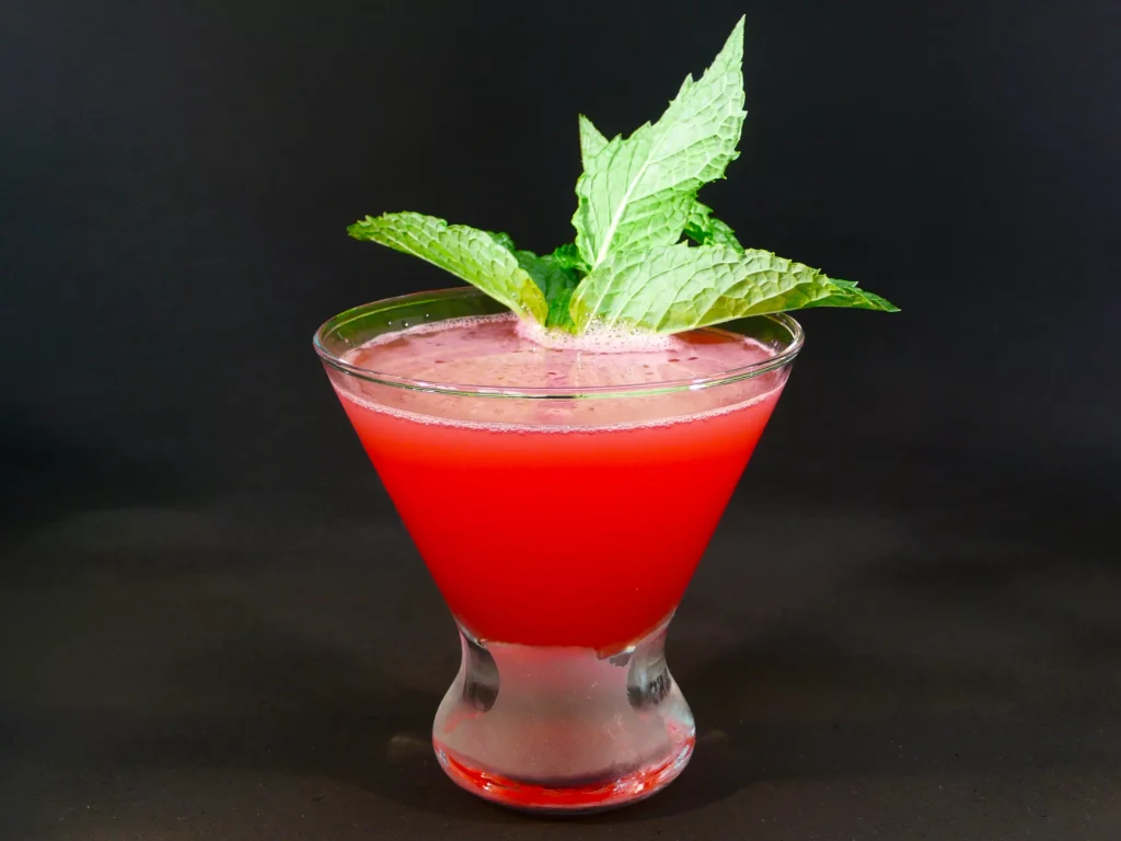 red drink with green letuce placed in a small glass