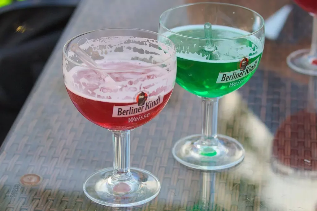 two wine glasses full of green and red liquid