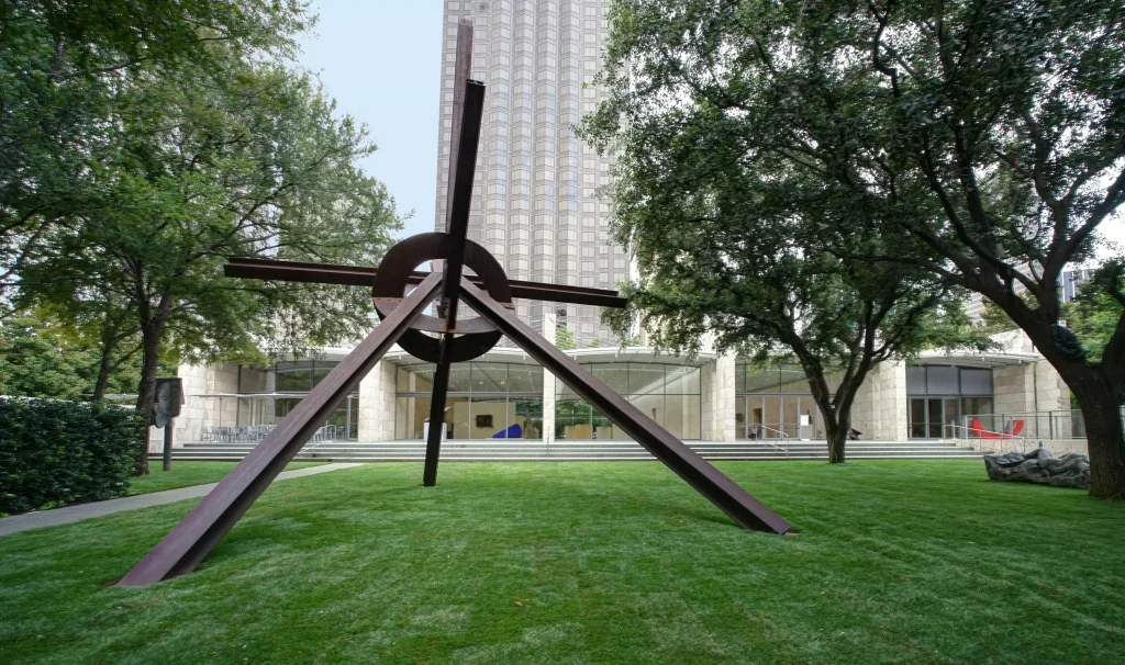 a park infront of a building with an art structure