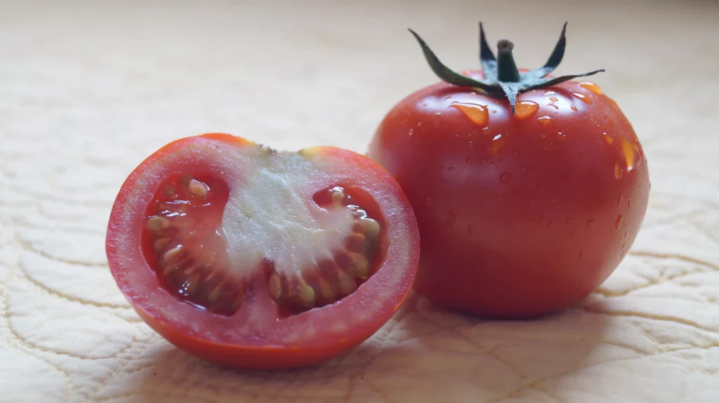 one whole and one half of a tomatoe on a table