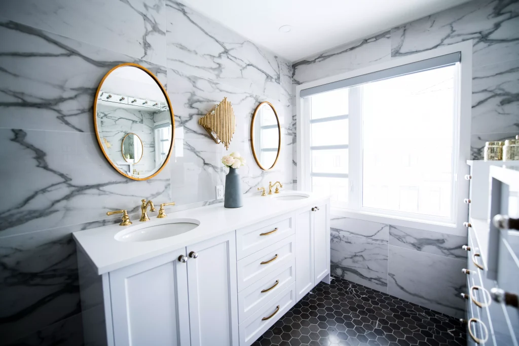 a bathroom with white color closets and circle looking mirrors next to a window