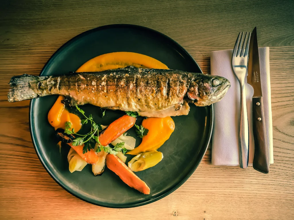 a fish and carrot on a blue plate