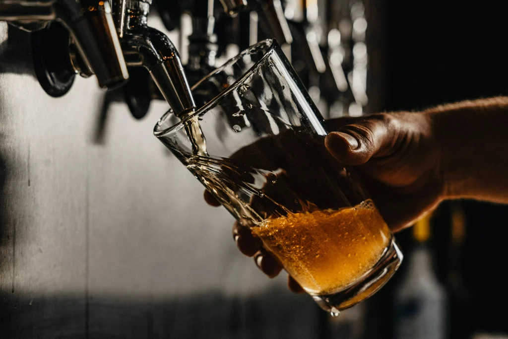 a person filling a glass bootle with beer