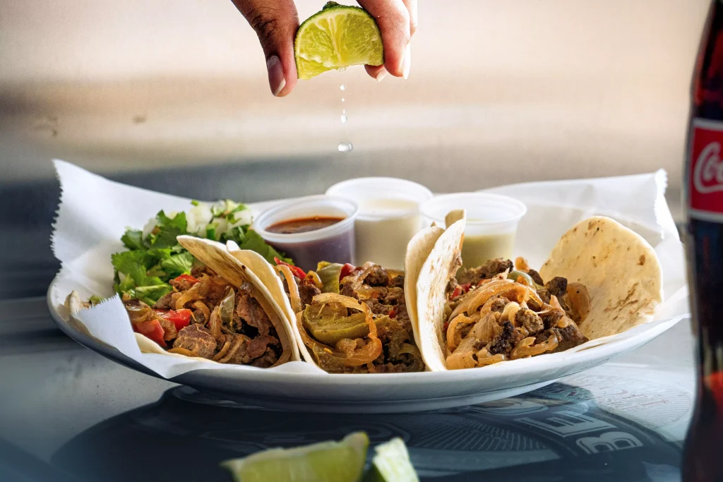 a person squezzing a lime on tacos