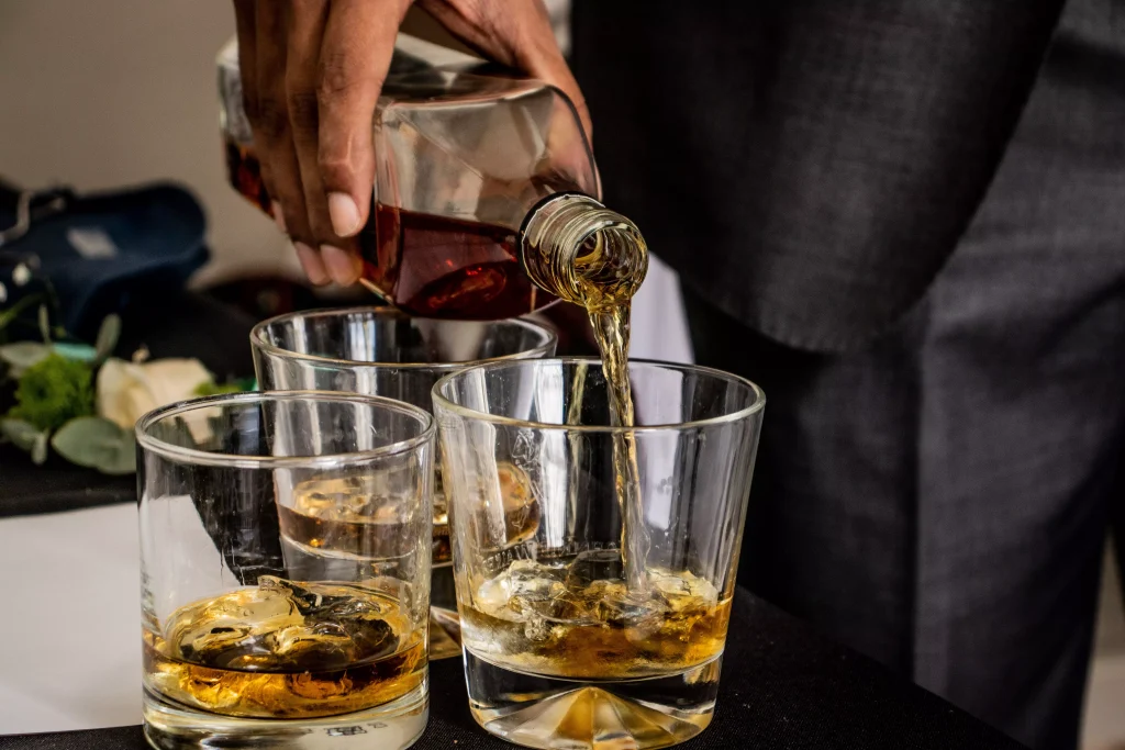 a person pouring drinks in three different glasses