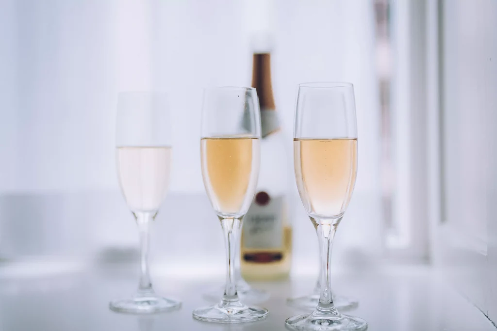 three wine glasses next to a bottle on the table