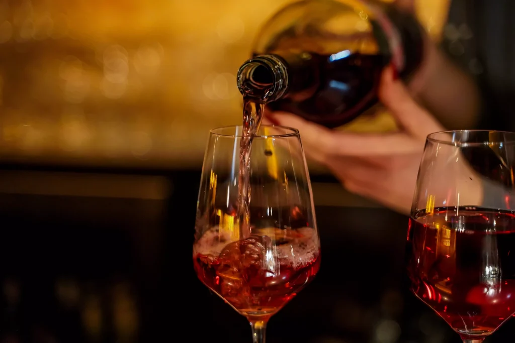 person siping wine from a bottle inside a glass