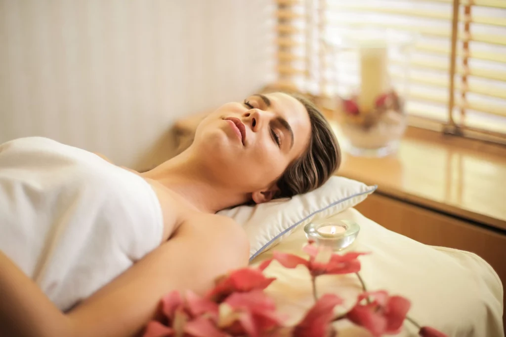 a women sleeping next to some flowers besides the window