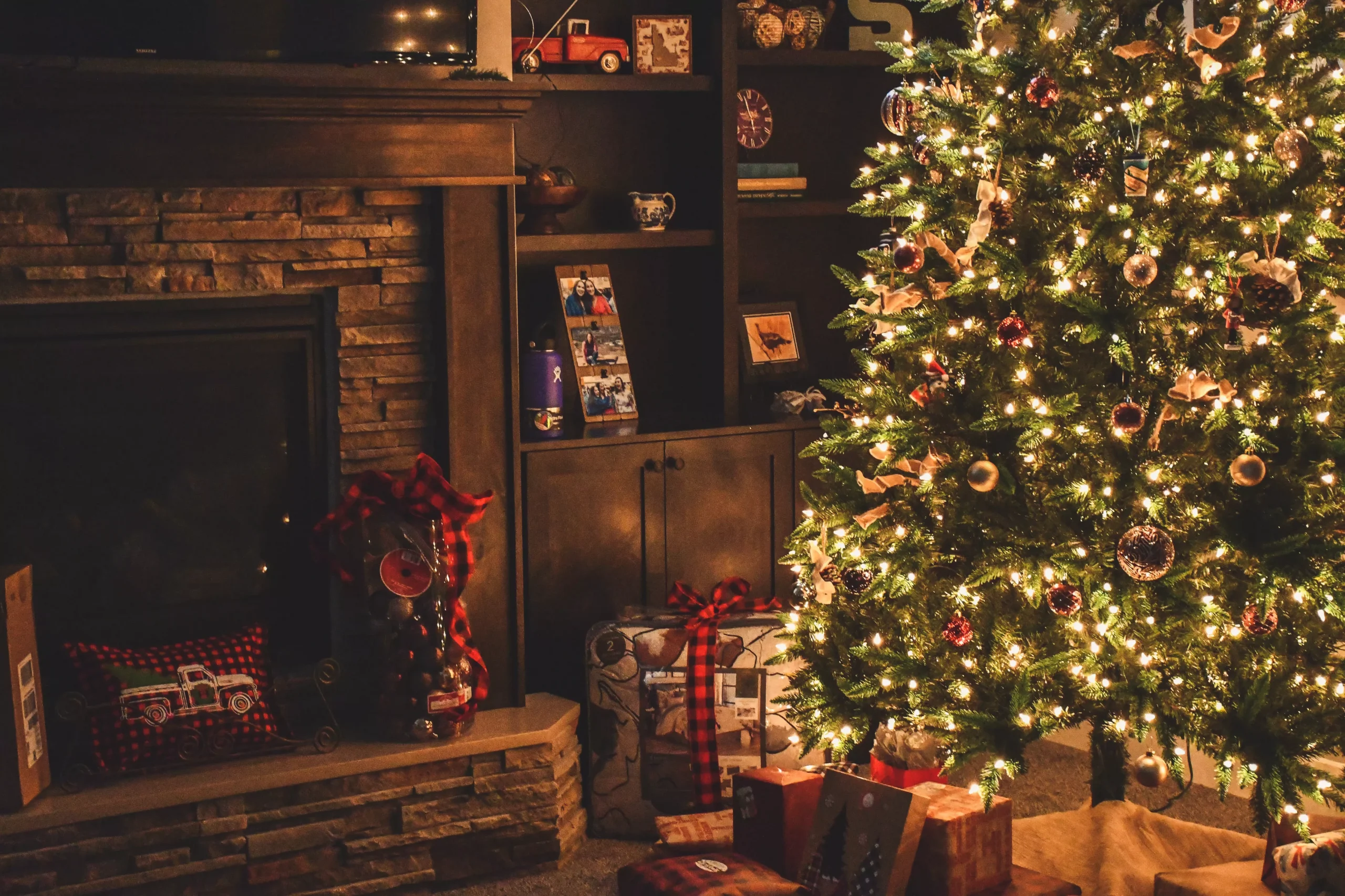 a tv and books next to a fully decorated Christmas tree