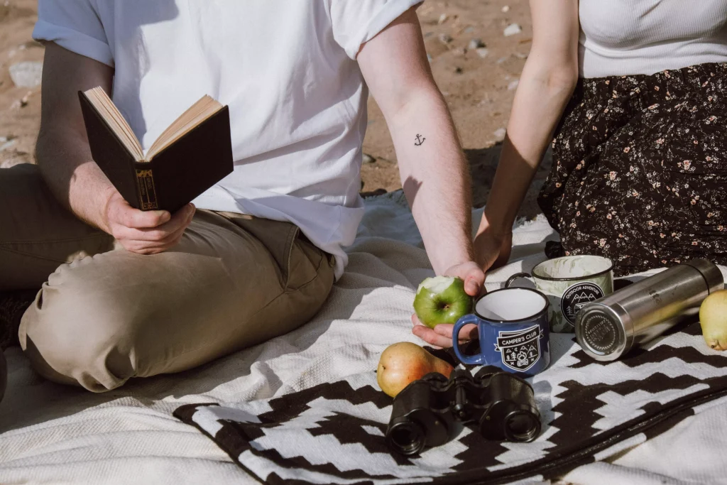 a guy in a white shirt and a girl in a blue dress having a picnic