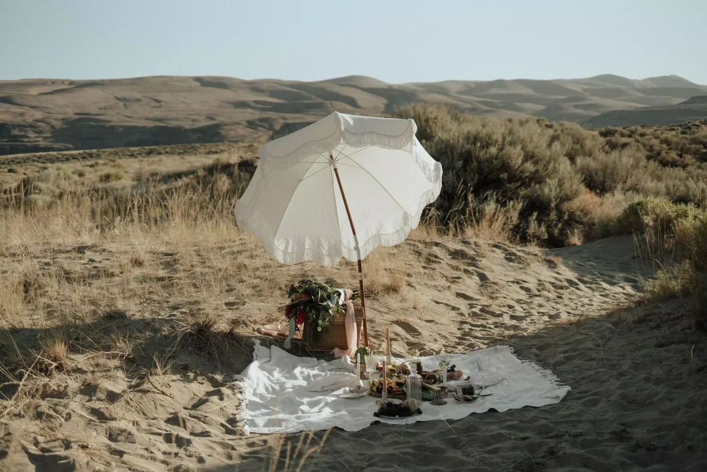 a blanket and a white umberella on sand