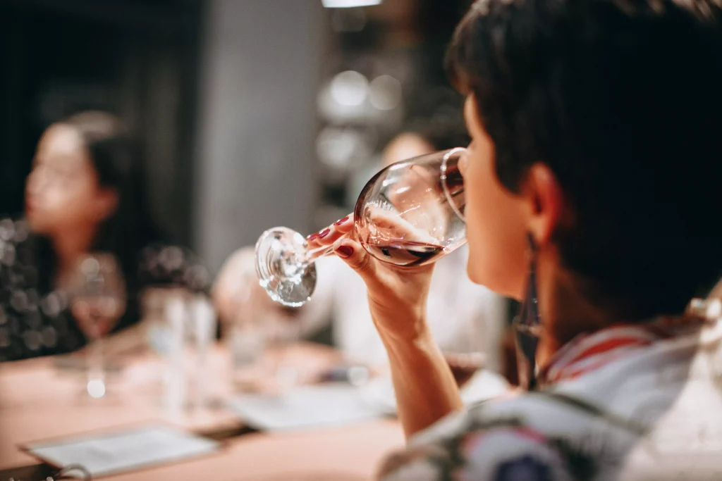 a girl with earrings drinking wine