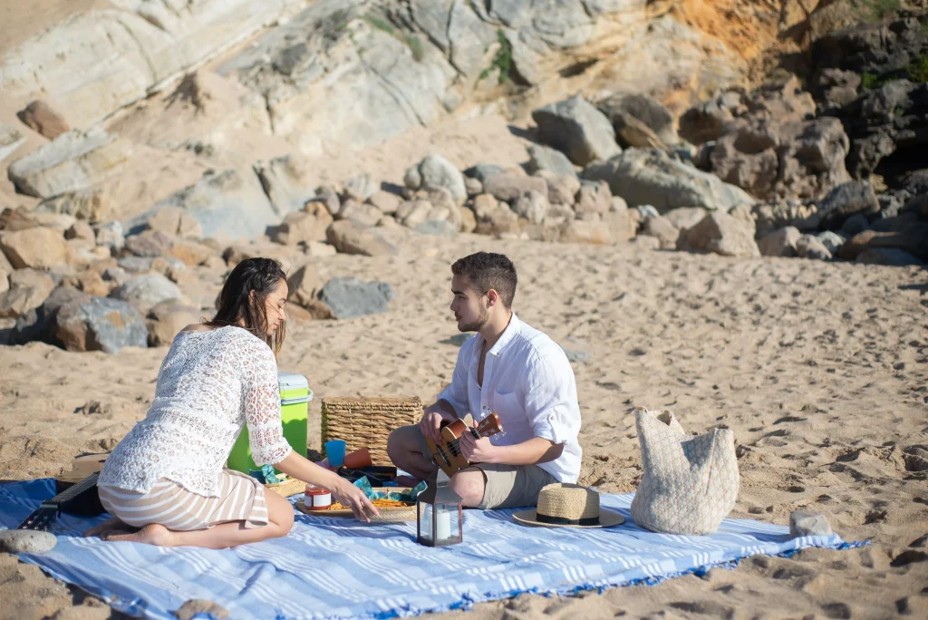 a guy and a girl having a picnic on the beach