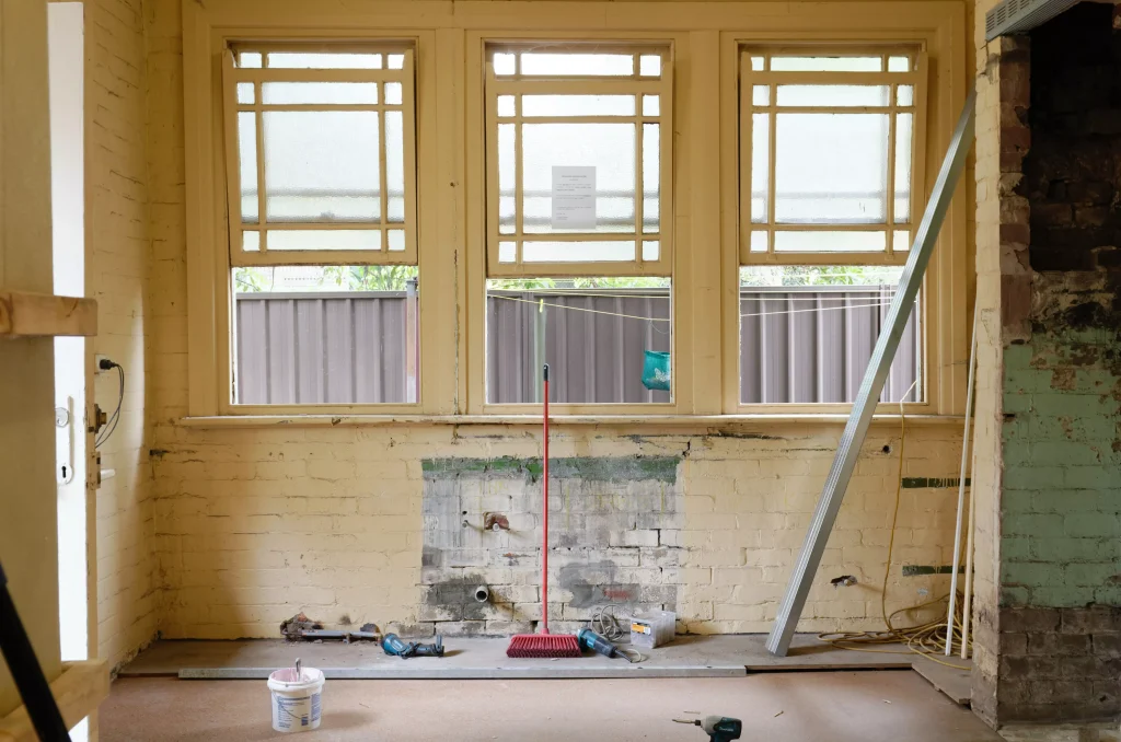 a living room with three windows photographed in the phase of renovating 