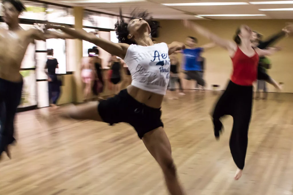 girl in a white shirt with other people dancing in a studio