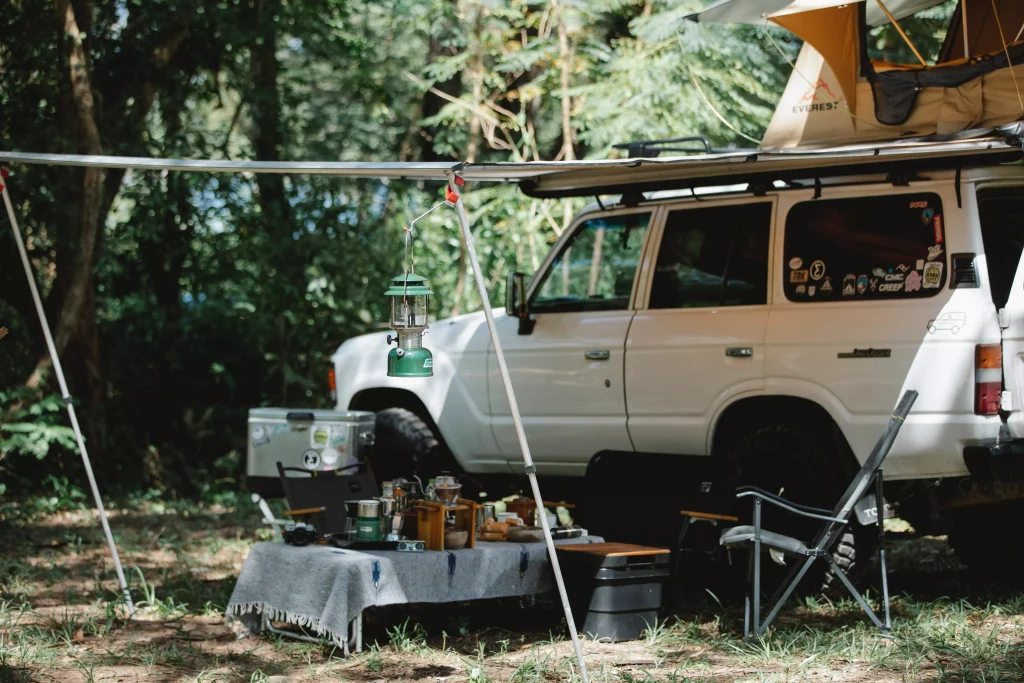 a white car next to a tent with a table and chairs in it