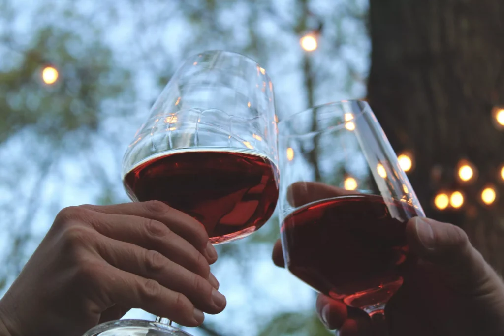 two persons holding wine glasses together