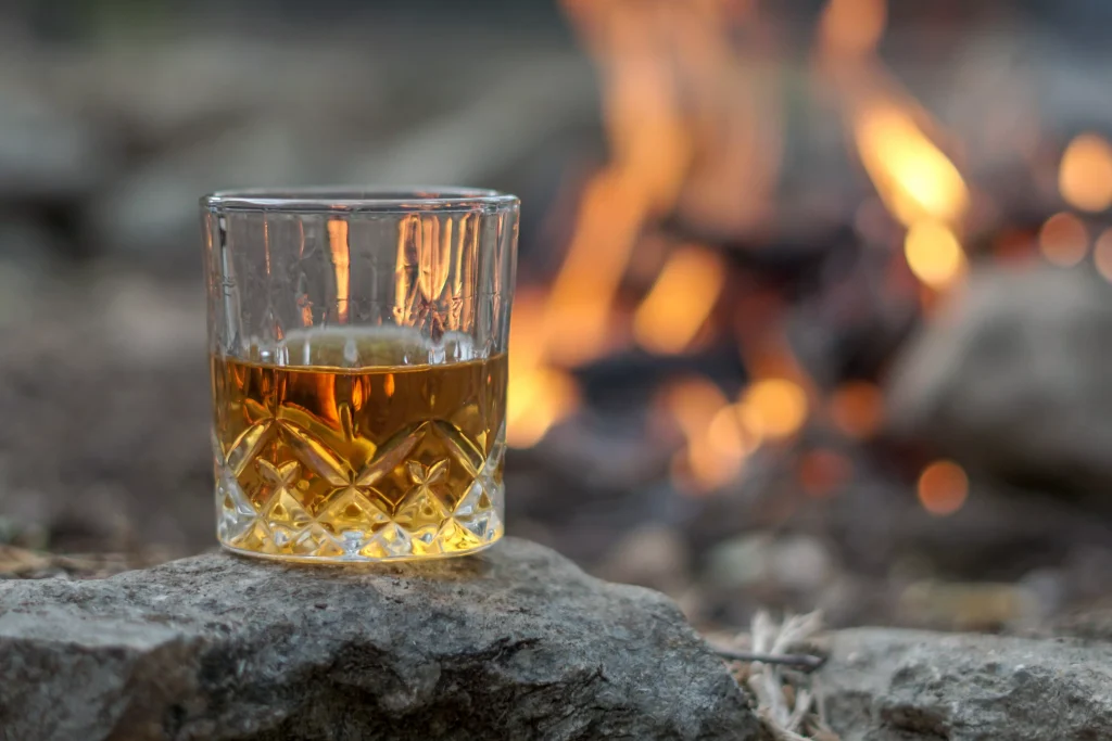 a glass half full next to a camp fire