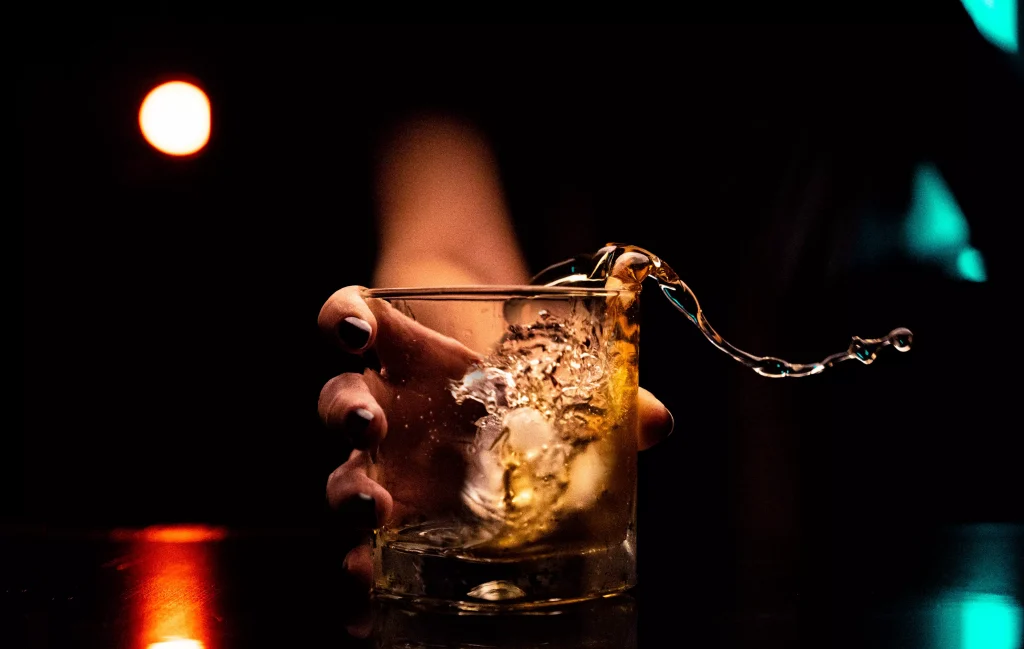 a person spilling a drink from a glass