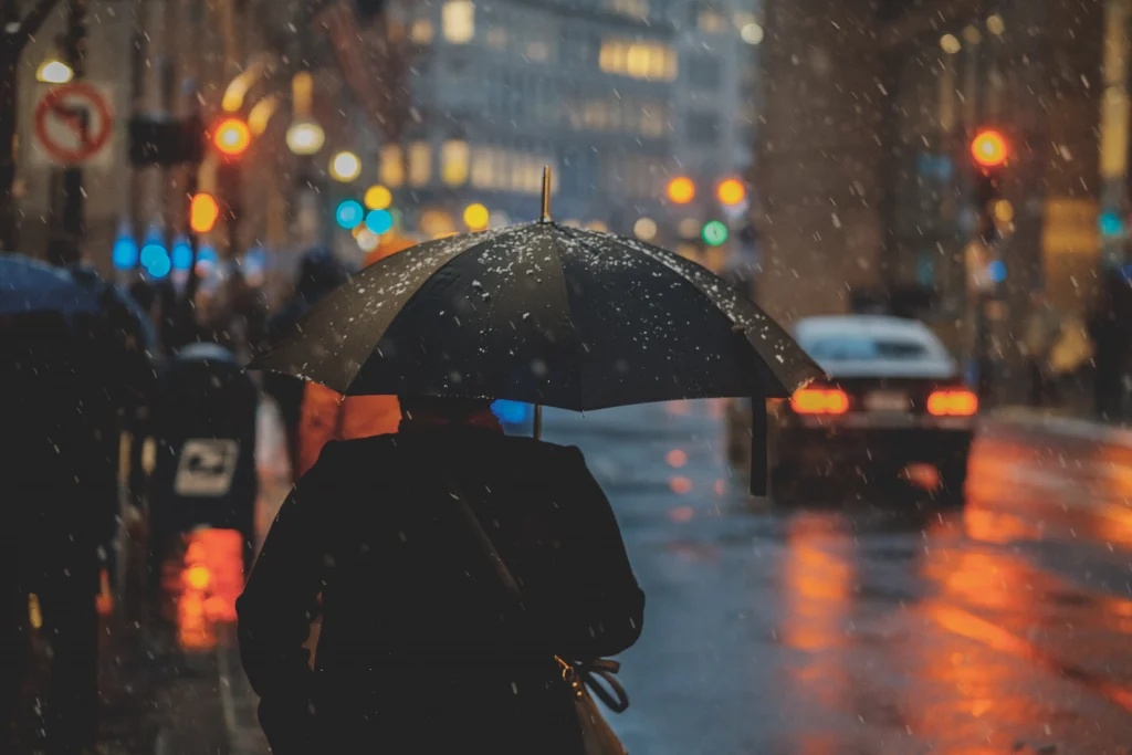 a person in a coat holding an umbrella on a rainy day