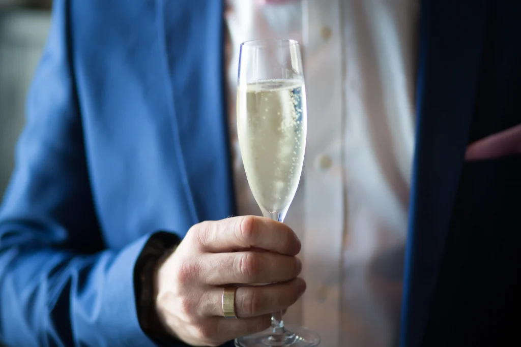 a man in a blue suit holding a glass full of champagne